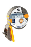 The Sea To Summit Bomber Tie Down, measuring 3 meters (10 feet) in length, is constructed with durable polyester webbing and includes a yellow silicone protector pad. It features a die-cast buckle with a maximum capacity of 250 kilograms (551 pounds).