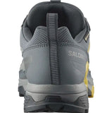 Rear view of a gray and yellow Salomon X Ultra 5 Men's Hiking Shoe, showcasing a textured Contagrip sole and heel pull tab, designed with Stability Advanced Chassis for enhanced support.
