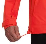 A person adjusts the drawstring at the hem of a bright orange Mammut Alto Light HS Men's lightweight hiking jacket.