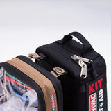 A black Survival Travel First Aid Kit by Survival First Aid, with a red label, is attached to a tan pouch. Both have zippers and clear windows showing contents like the SMART Bandage, ideal for remote outdoor adventures.