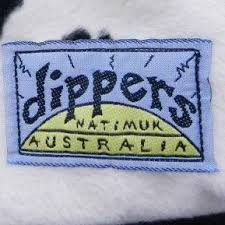 Embroidered clothing label reading "Dippers Chalk Bag, nat. mix, Australian made" with a blue border and stylized text on a textured white fabric background.