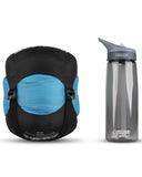 A blue and black stuff sack for a Sea to Summit Venture VTI Sleeping Bag is next to a clear CamelBak Eddy water bottle with a grey lid and integrated straw.