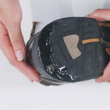 A person holding a shoe with visible wear on the sole, ready to revive it using Gear Aid Aquaseal Shoe Repair Glue, a trusted adhesive by Gear Aid.