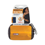 Packaging for a Sea to Summit Reactor Thermolite sleep liner, featuring an image of a man and product details, alongside the liner in a storage sack.