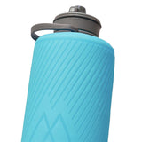 Close-up of the Hydrapak Flux Bottle 1.5L, lightweight and turquoise with a textured design, gray lid, carrying handle, and high flow nozzle for easy hydration.
