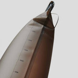 Close-up of the HydraPak Force Bladder, a brown hydration water bag with a vertical milliliter measurement scale, shown on a light grey background.
