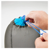 A person is using a Sea to Summit Mesh Stuff Sack to tie up a bag for gear organization.