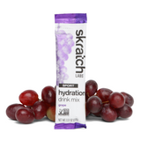 A Skratch Labs Sport Hydration Mix single serve packet displayed next to a cluster of red grapes, packed with electrolytes.