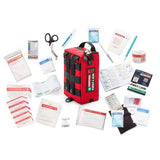 Image shows the Survival First Aid's Survival Handy First Aid Kit in red, surrounded by various medical supplies, including an emergency blanket, bandages, scissors, tape, gloves, antiseptic wipes, a CPR mask, and instruction manuals.