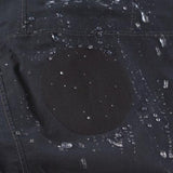 Close-up of a black fabric piece with water droplets on it, highlighting a round black patch in the center, ideal for demonstrating Gear Aid's Gore-Tex Fabric Patches and their adhesive-backed repair capabilities.
