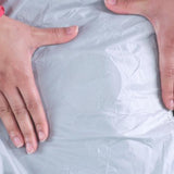 A person's hands are on top of a plastic bag, applying Gear Aid Tenacious Tape Repair Patches to outdoor gear.