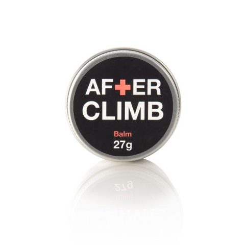 A small, round tin labeled "Club Strong After Climb Hand Balm 27g" with beeswax on a reflective white surface.