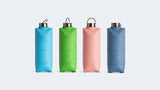 Four DiFold Origami Bottles by Difold, made from plant-based polymer in blue, green, pink, and gray, are arranged in a row against a white background—ideal for zero waste shopping.