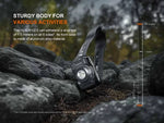 The Fenix Lighting HL12R V2.0 headlamp, shown outdoors on rocky ground, features a tough aluminum case, 500 lumens of brightness, drop resistance up to 1.5 meters, and efficient SST20 white & 2835 red LEDs—a vertical scale indicates the drop height.
