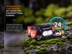 The Fenix Lighting HM65R-T V2.0 headlamp rests on moss, showcasing a 24-hour runtime and hands-free lighting—ideal for overnight trail running with its Luminus SST40 & OSRAM GW PUSTA1.PM LEDs.