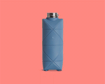The DiFold Origami Bottle by Difold is a blue, collapsible water bottle featuring a geometric pattern, made from plant-based polymer, presented in both expanded and compressed forms on a solid pink background.