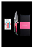 The Koi "Garry" | The Galah EDC Pocket Knife, from Koi Knives, features a stylish pink handle and is elegantly displayed next to a sleek black box. Accompanied by a card showcasing a charming pink bird, this outdoor knife perfectly combines functionality with flair, making it ideal for camping.