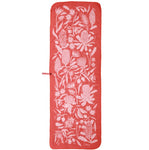 A rectangular sleeping bag with white floral patterns in a red color, crafted from recycled polyester for environmentally conscious adventures and designed with a small attached strap.