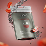 A pack of Radix Ultra 800kCal Meals, ideal for highly active individuals, surrounded by splashes of water and floating tomato slices against a neutral background. This plant-based, gluten-free meal from Radix weighs 159g (5.6 oz).