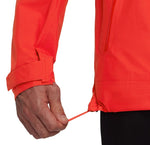 A person adjusts the drawstring at the hem of a bright orange Mammut Alto Light HS Men's lightweight hiking jacket.