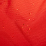Water droplets on textured red fabric highlight the PFC-free durable water repellent finish of the Mammut Alto Light HS Men's hiking jacket by Mammut.