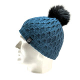 A mannequin head showcases the Domex Beanie by Domex—a blue knit beanie featuring a black faux fur pom-pom and a small black logo tag—ideal for anyone looking for warm, stylish winter hats.