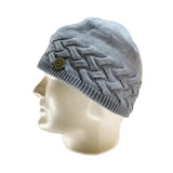 The Domex Beanie by Domex is a light gray knit hat featuring a braided pattern and round metallic logo on the side, shown on a white mannequin head—ideal for anyone wanting a warm, stylish winter beanie.