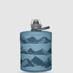 The HydraPak Hydrapak Stow Bottle 500ML is a blue collapsible bottle with dark and light blue mountain range graphics, featuring a spill-proof nozzle for easy, mess-free hydration.