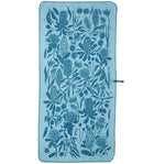 The Mont Flora Microfibre Travel Towel by Mont is a rectangular towel made from quick-drying recycled polyester. It displays a dark blue floral pattern with various botanical elements on a blue background and includes a small strap on the side, making it ideal for travel.