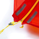 Close-up of a red fabric item with a yellow zipper and gray Velcro strips. Crafted from durable materials, it includes a yellow string with a black clip attached to the zipper pull. Ideal for packing into the Mont Moondance EX Tent by Mont, perfect for ultralight backpacking adventures.