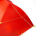 Close-up of the Mont Moondance EX Tent in red, featuring yellow guylines and stakes for secure setup, made from durable materials perfect for ultralight backpacking.