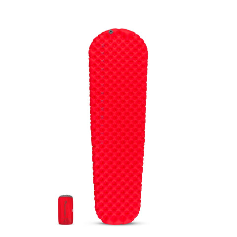 The Sea to Summit Comfort Plus Insulated Air Sleeping Mat is shown fully inflated in bright red, featuring Exkin Platinum insulation, with a matching red stuff sack beside it for scale.
