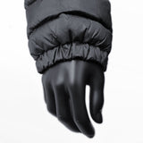 A close-up of a black mannequin hand with a puffy, quilted black sleeve from a 3 Peaks Men's Down Jacket resting over it. The sleeve's elastic cuff fits snugly around the mannequin's wrist, promising high warmth for those chilly days.