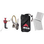Camping stove set including a red fuel pump, MSR - Whisperlight International Multi Fuel Stove, black storage bag, and two silver heat reflectors isolated on a white background.