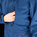 A person wearing a blue jacket with a logo labeled "Mont" is unzipping the chest pocket of their Mont Men's Austral JKT.
