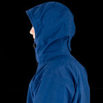 Side view of a person wearing a blue Mont Men's Austral JKT made from Hydronaute fabric against a black background.