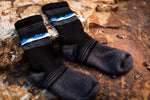 A pair of black and blue Wilderness Wear Grampians Peaks Hiker socks, elegantly resting on a rock in the Grampians.