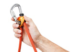 A hand holding a Petzl Connect Adjust carabiner, used for sport climbing.