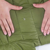 A person's hands applying the Gear Aid Tenacious Tape Repair Patches on a green jacket.