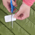 A person using Gear Aid Tenacious Tape Repair Tape to repair a piece of outdoor gear, such as a sleeping bag.